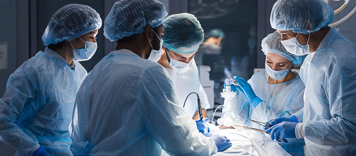 Group of concentrated surgeons engaging in rescue of male patient in operation room at hospital, emergency case, surgery, medical technology, health care and disease treatment concept