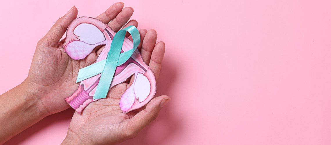 Teal awareness ribbon with cervix shape on palms hand over pink